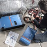 Tecnico C-Lover controlla gli impianti di un camper furgonato usato: inverter Victron, cablaggio e schema elettrico durante l'ispezione pre-vendita